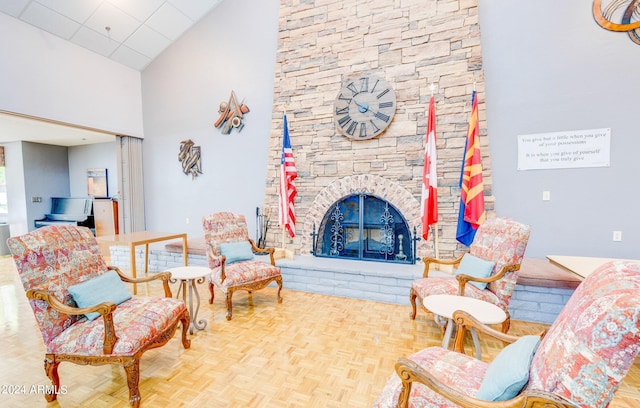 living room with high vaulted ceiling, a stone fireplace, and parquet flooring