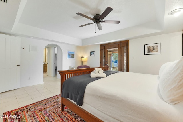 tiled bedroom featuring a tray ceiling, access to exterior, and ceiling fan