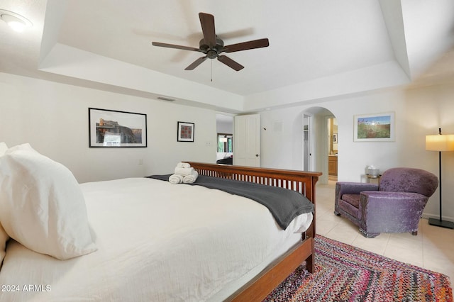 bedroom featuring ceiling fan, a raised ceiling, and light tile patterned floors