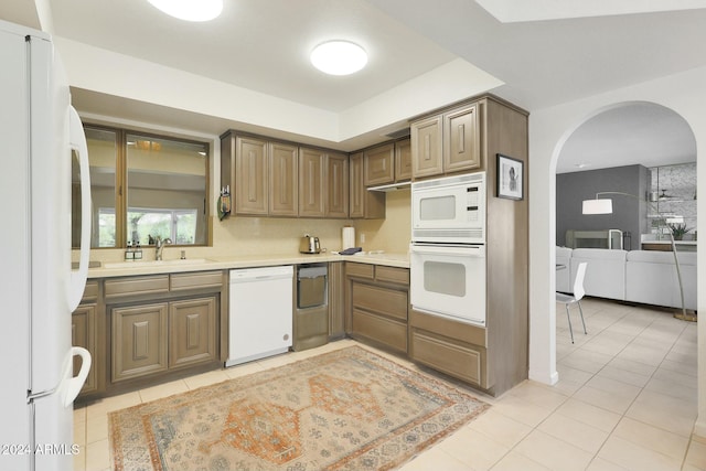 kitchen with light tile patterned flooring, white appliances, and sink