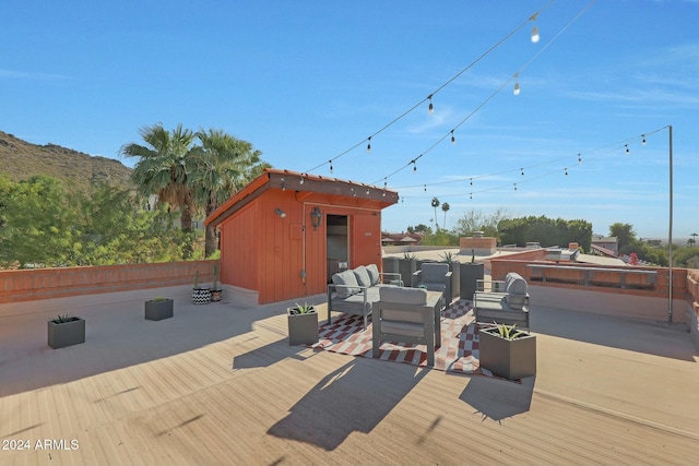 wooden terrace featuring outdoor lounge area, a mountain view, and a storage shed