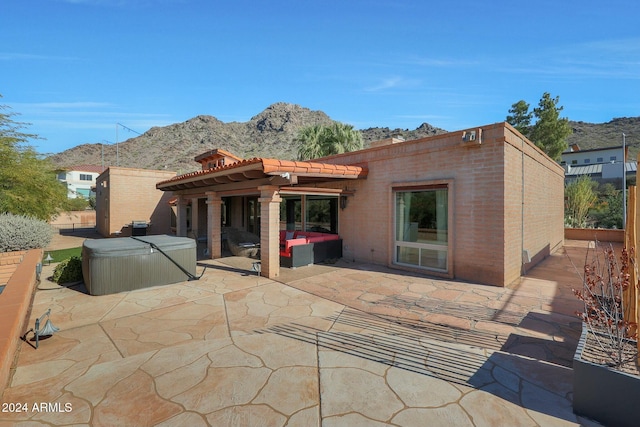 back of property with a mountain view, a patio, and a hot tub