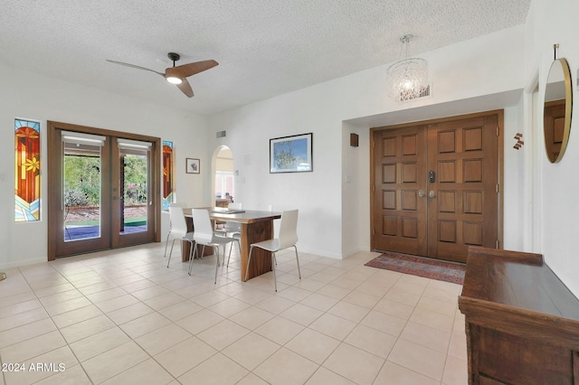 dining space with a textured ceiling, french doors, light tile patterned flooring, and ceiling fan with notable chandelier