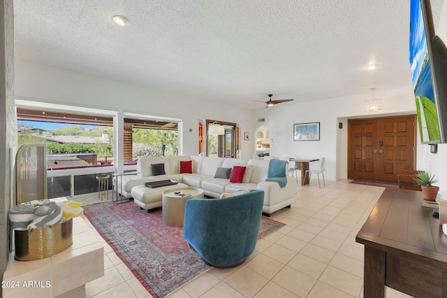 living room with ceiling fan, light tile patterned flooring, and a textured ceiling