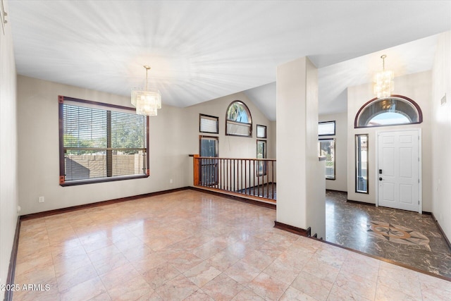 entrance foyer featuring a chandelier, vaulted ceiling, and baseboards