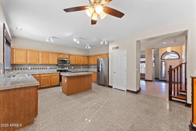 kitchen with a sink, visible vents, baseboards, appliances with stainless steel finishes, and backsplash