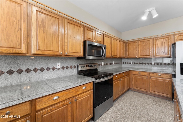 kitchen with appliances with stainless steel finishes, brown cabinetry, and tile countertops