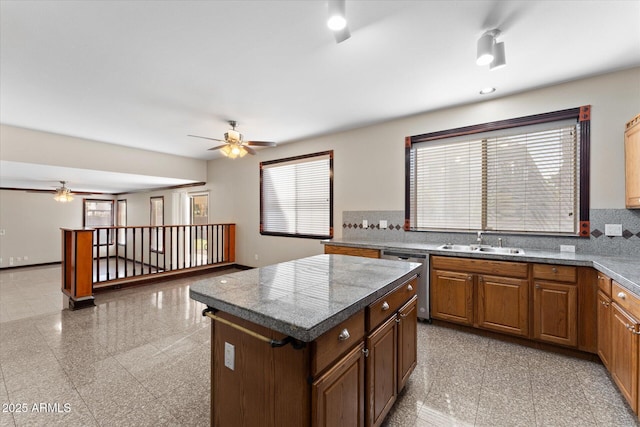 kitchen with tile countertops, granite finish floor, stainless steel dishwasher, a sink, and plenty of natural light