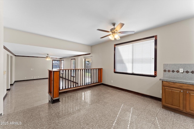 empty room featuring granite finish floor, baseboards, and ceiling fan