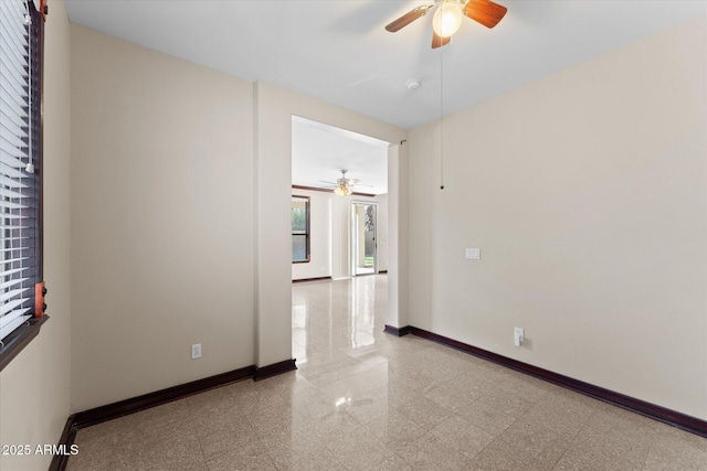 spare room featuring granite finish floor, a ceiling fan, and baseboards