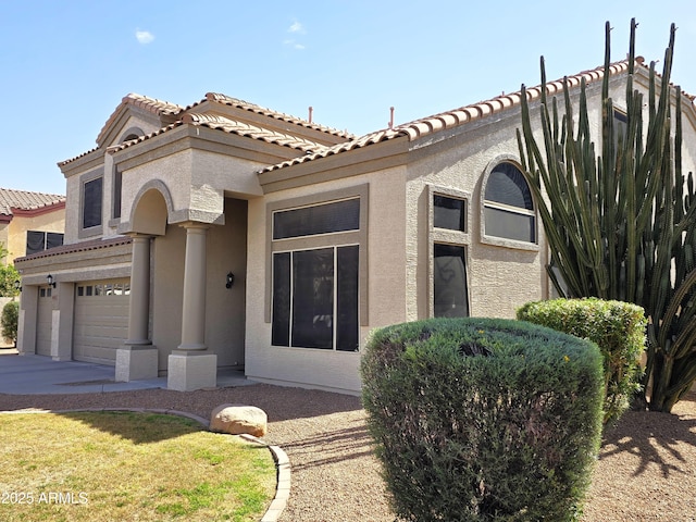 mediterranean / spanish-style house with an attached garage, concrete driveway, and stucco siding