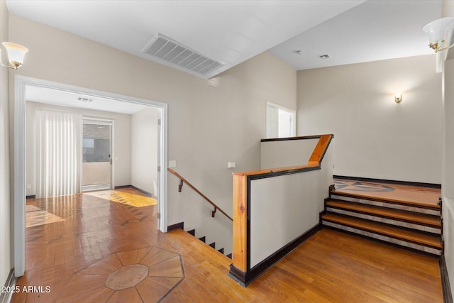 staircase with baseboards, wood finished floors, visible vents, and a healthy amount of sunlight