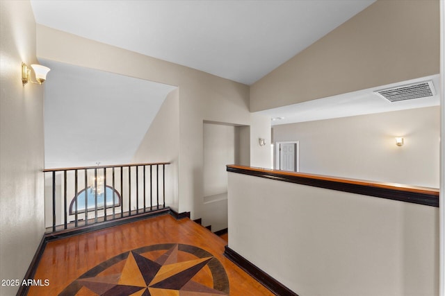 hall featuring visible vents, vaulted ceiling, an upstairs landing, wood finished floors, and baseboards