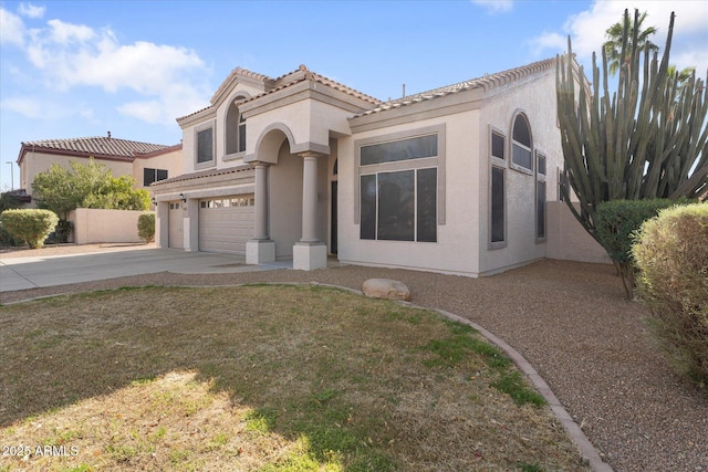 mediterranean / spanish home featuring concrete driveway, a tile roof, an attached garage, and stucco siding