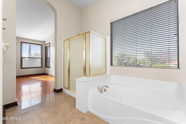 full bath with a stall shower, granite finish floor, a garden tub, and baseboards