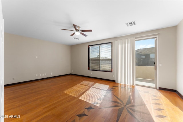 empty room featuring baseboards, visible vents, ceiling fan, and wood finished floors