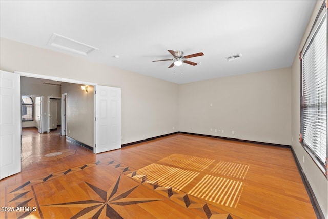 unfurnished room with attic access, visible vents, baseboards, and wood finished floors