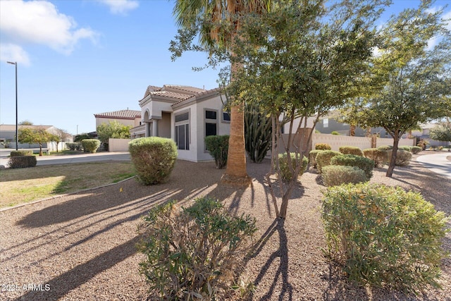 view of front of home featuring a tile roof, fence, and stucco siding