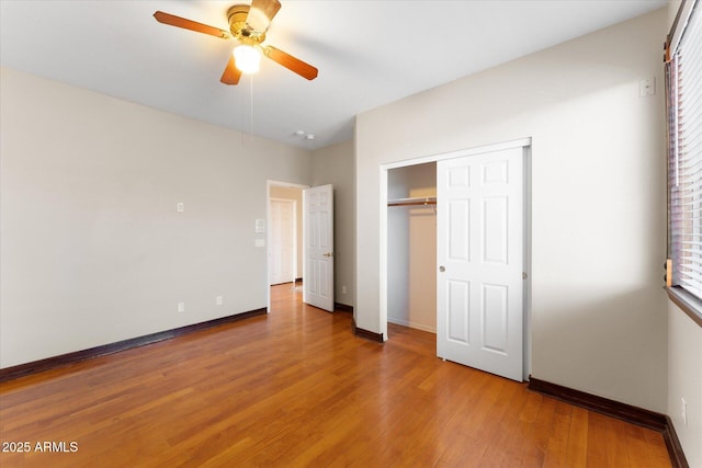 unfurnished bedroom featuring ceiling fan, a closet, light wood-style flooring, and baseboards