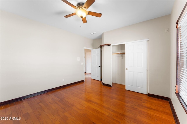 unfurnished bedroom featuring a ceiling fan, a closet, baseboards, and hardwood / wood-style flooring