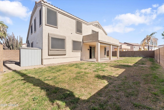 back of house with a tile roof, a yard, stucco siding, a patio area, and a fenced backyard