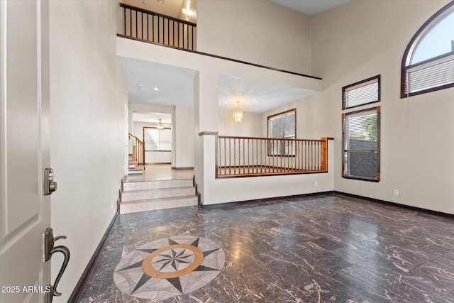 foyer with marble finish floor, baseboards, a high ceiling, and stairs