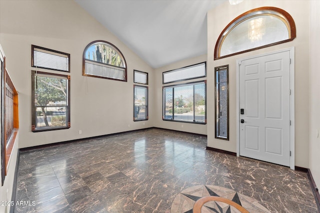 entrance foyer featuring high vaulted ceiling, marble finish floor, plenty of natural light, and baseboards