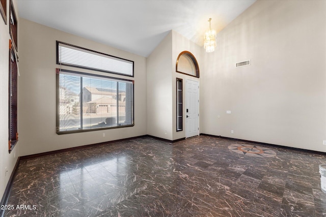 spare room with marble finish floor, visible vents, an inviting chandelier, high vaulted ceiling, and baseboards