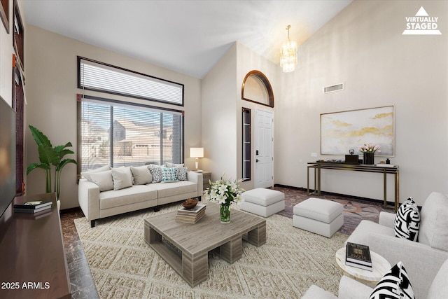 living room featuring a chandelier, a high ceiling, visible vents, and baseboards