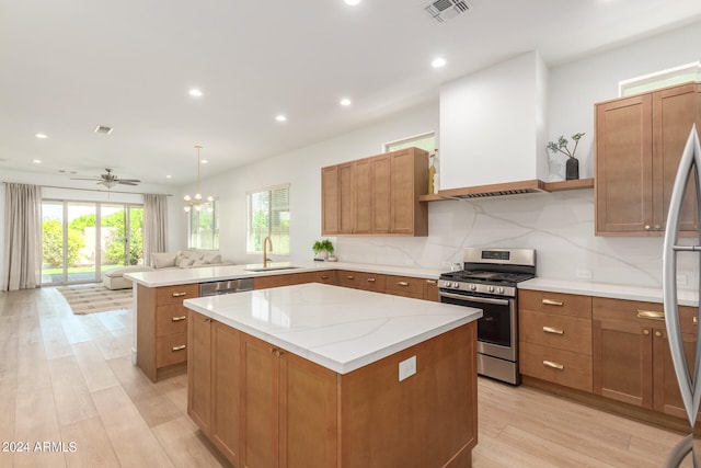 kitchen with appliances with stainless steel finishes, light wood-type flooring, sink, and a kitchen island