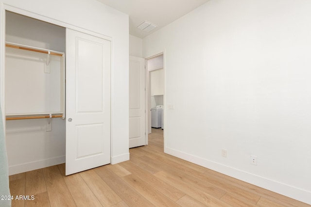 unfurnished bedroom featuring light hardwood / wood-style floors, washer / dryer, and a closet