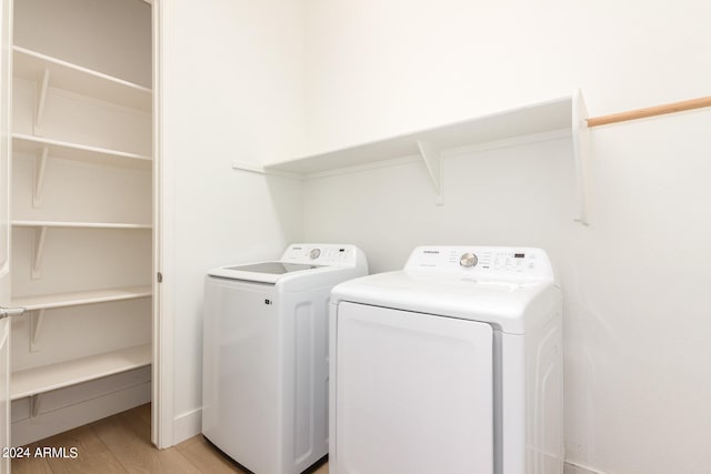 laundry area with washing machine and dryer and light hardwood / wood-style floors