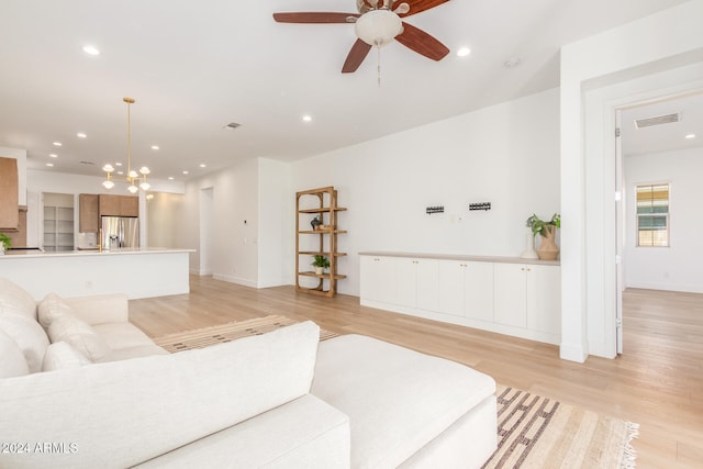 living room featuring light wood-type flooring and ceiling fan with notable chandelier