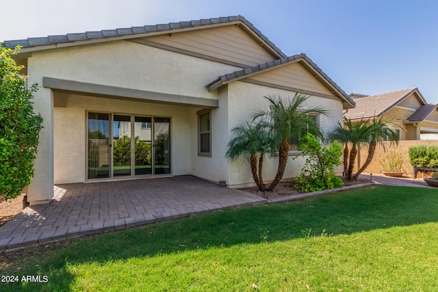 rear view of property featuring a patio and a lawn