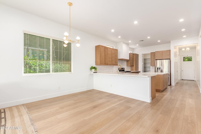 kitchen featuring hanging light fixtures, kitchen peninsula, light hardwood / wood-style flooring, stainless steel refrigerator with ice dispenser, and a notable chandelier