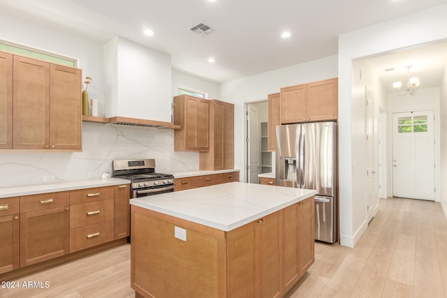 kitchen with light hardwood / wood-style floors, tasteful backsplash, a notable chandelier, a kitchen island, and appliances with stainless steel finishes