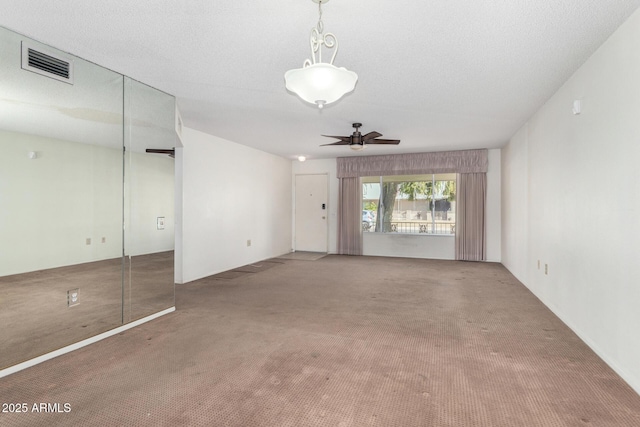 carpeted spare room with ceiling fan and a textured ceiling