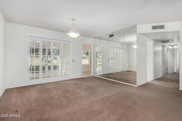 carpeted empty room with a textured ceiling and french doors