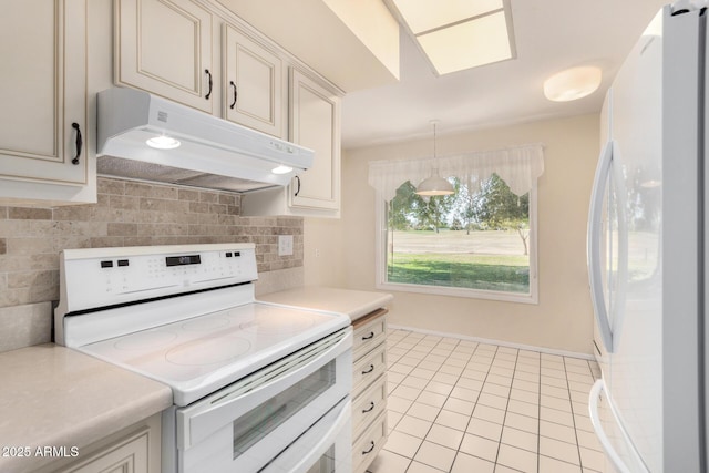 kitchen featuring light tile patterned flooring, white appliances, decorative light fixtures, and backsplash