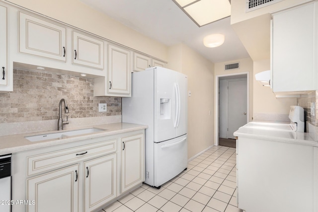 kitchen with cream cabinets, sink, light tile patterned floors, and white appliances