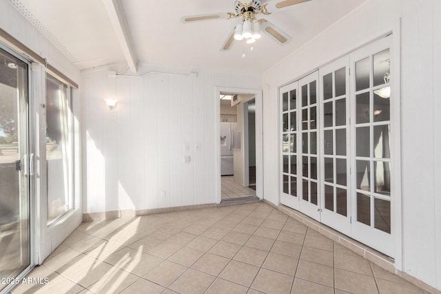 tiled spare room with beamed ceiling, plenty of natural light, ceiling fan, and wood walls