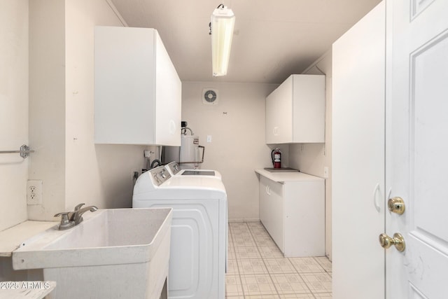 washroom featuring washer and clothes dryer, cabinets, sink, and water heater