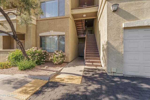 property entrance featuring a garage, a balcony, and stucco siding