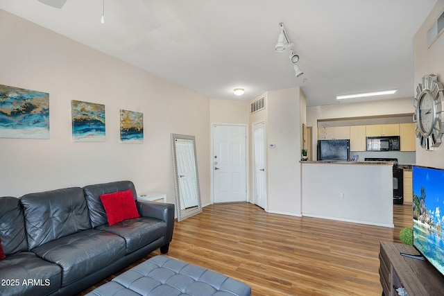 living room featuring visible vents, light wood-style flooring, ceiling fan, and baseboards