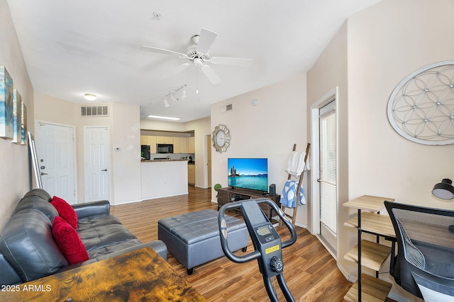 living area with a ceiling fan, rail lighting, light wood-style flooring, and visible vents