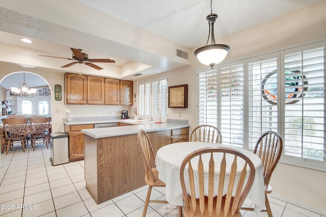 kitchen with pendant lighting, light tile patterned floors, a textured ceiling, a raised ceiling, and kitchen peninsula