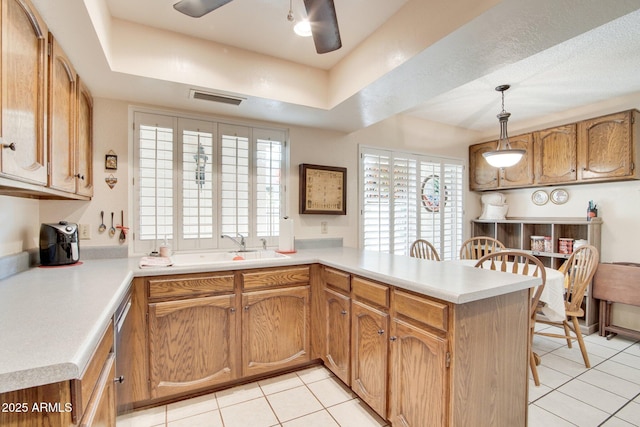 kitchen featuring light tile patterned flooring, decorative light fixtures, sink, kitchen peninsula, and a raised ceiling