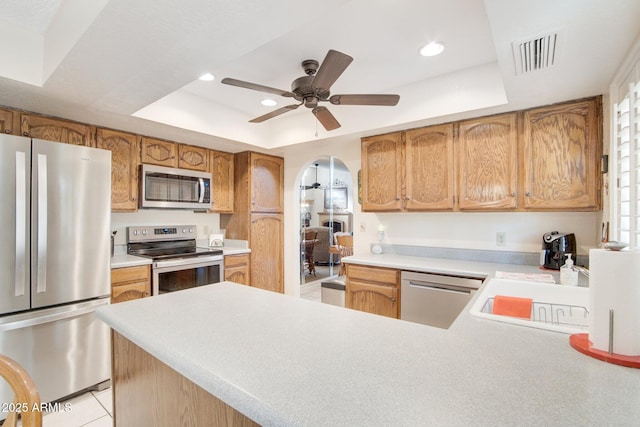 kitchen featuring ceiling fan, appliances with stainless steel finishes, a raised ceiling, and sink