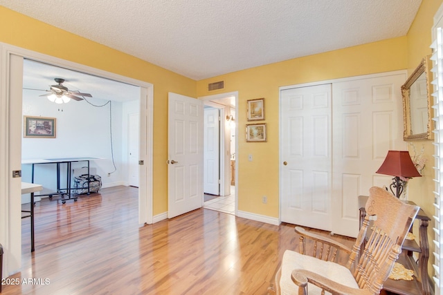 living area with ceiling fan, hardwood / wood-style floors, and a textured ceiling