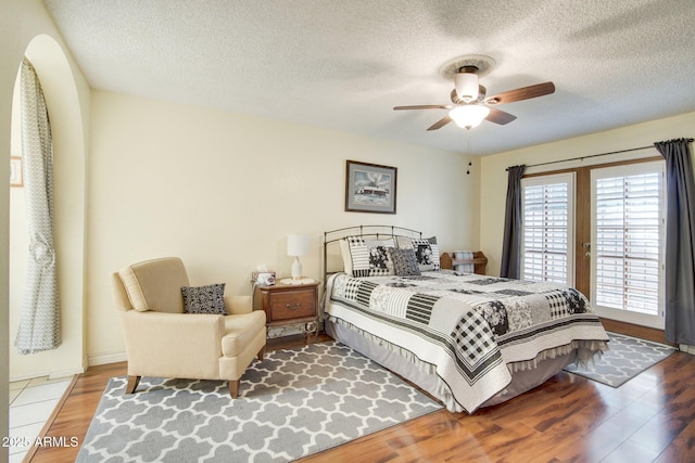 bedroom with ceiling fan, hardwood / wood-style floors, and a textured ceiling